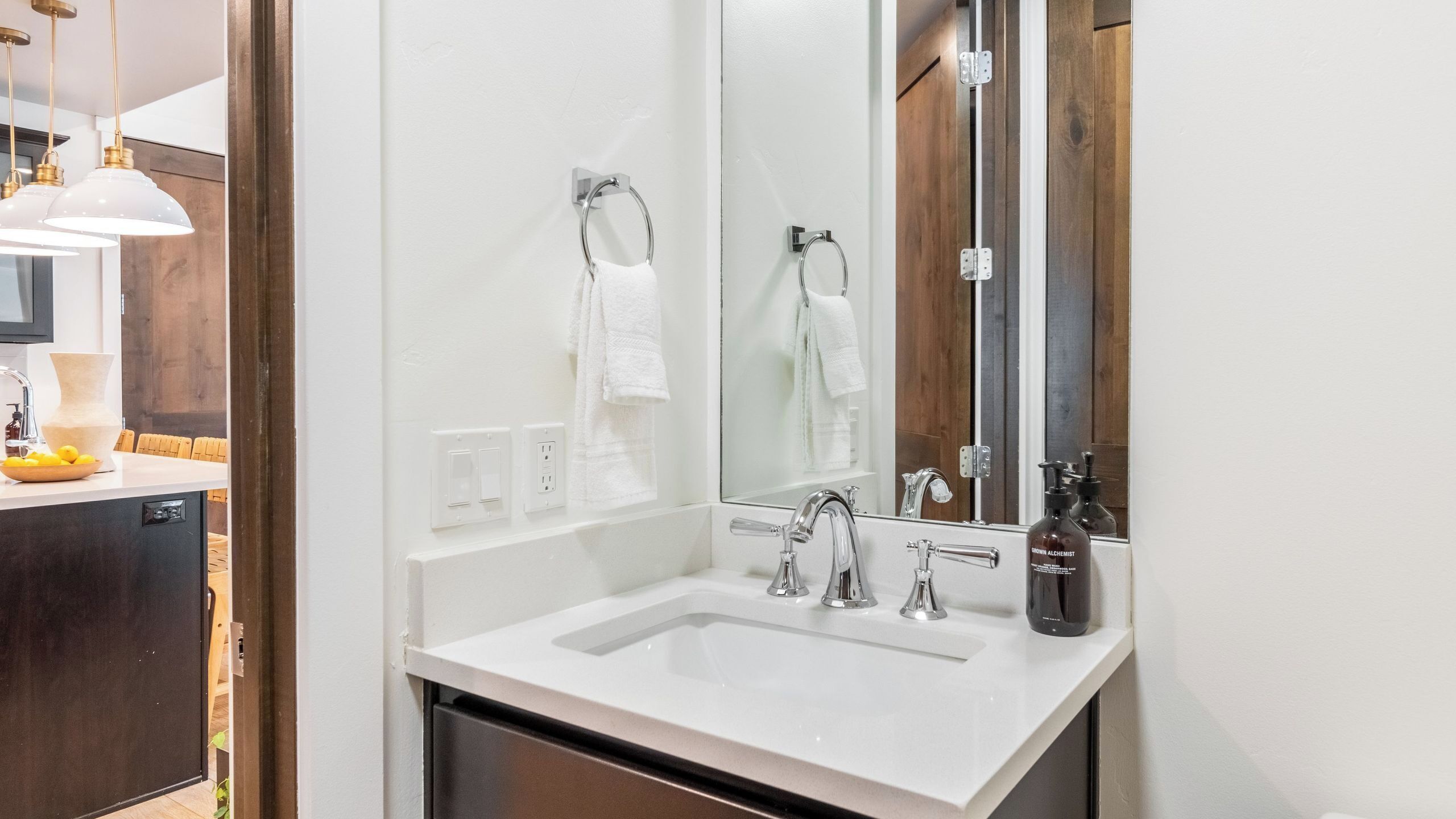 A bathroom with a white sink, two faucets, a mirror, and a towel rack.