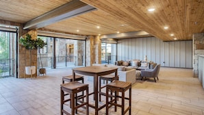 A spacious indoor area with a wooden ceiling, stone walls, and a mix of seating arrangements including a round table and chairs, sofas, and a dining table. - Kokopelli by Avantstay Close to the Ski Slopes in This Majestic Home in Park City (Park City)