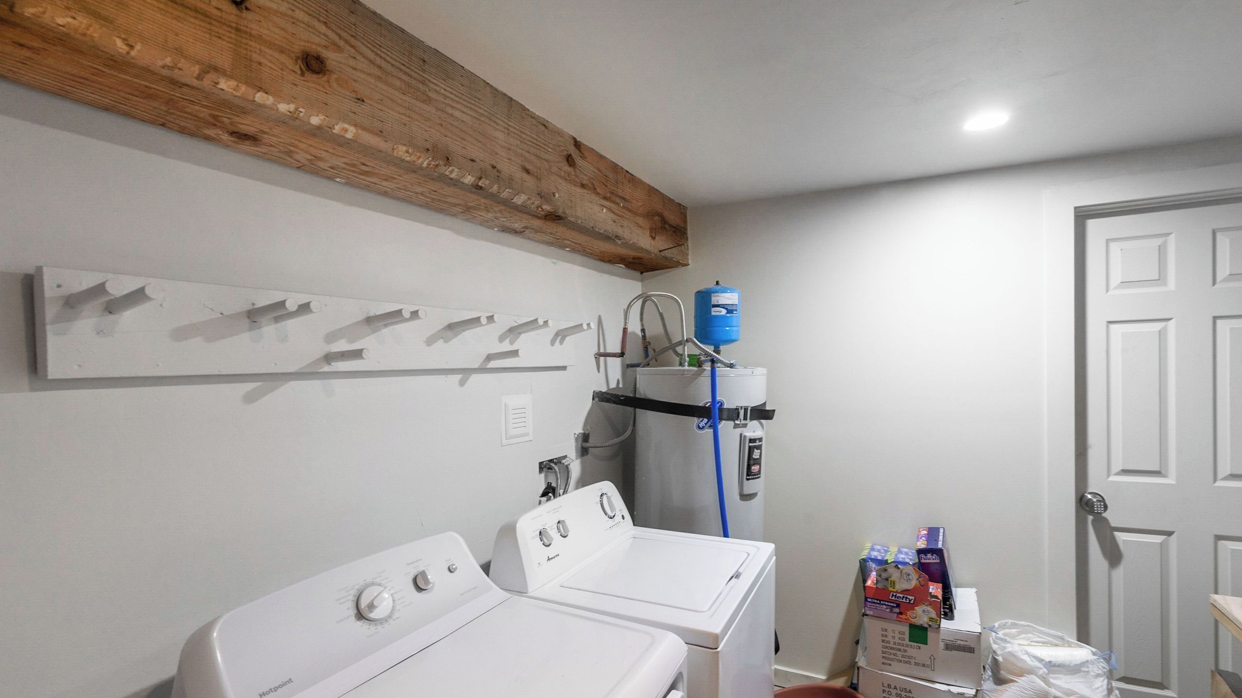 A laundry room with two white washing machines, a water heater, and a water filter.