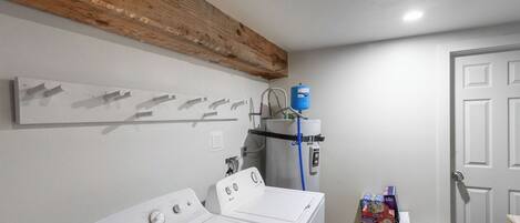 A laundry room with two white washing machines, a water heater, and a water filter.