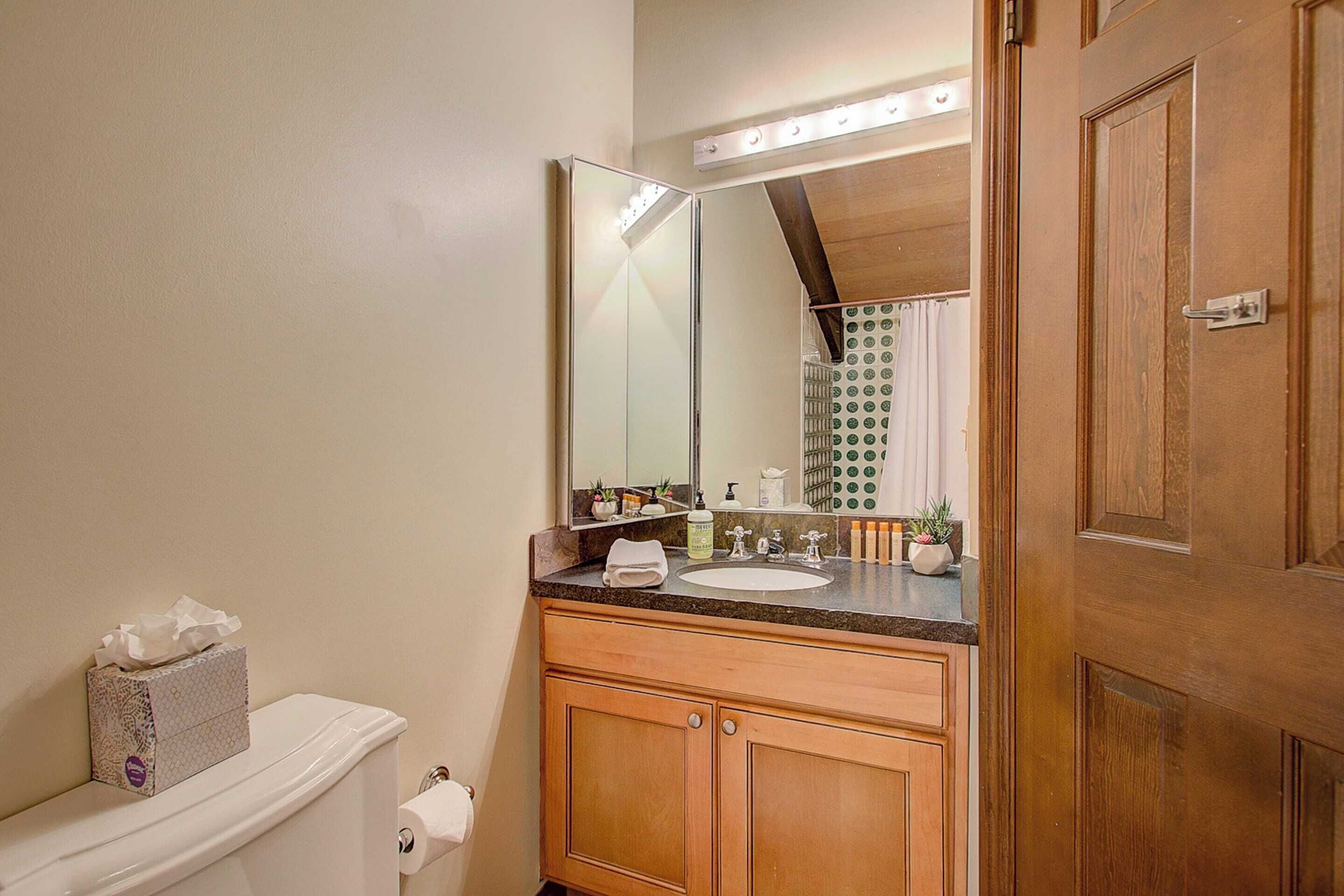 A bathroom with a wooden vanity, a mirror, a toilet, and a sink.