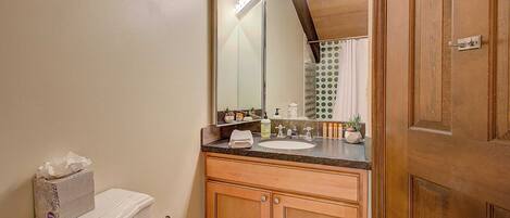 A bathroom with a wooden vanity, a mirror, a toilet, and a sink.