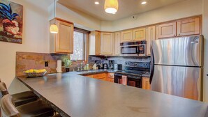 A modern kitchen with a large island, stainless steel appliances, wooden cabinets, and pendant lighting. - Slope-side Townhome Steps to Main St, Deck View of Old Town Quittin Time Townhome by Avantstay (Park City)