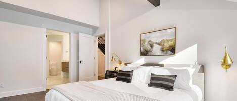 Un dormitorio con cama, mesita de noche, lámpara de pared y un cuadro.