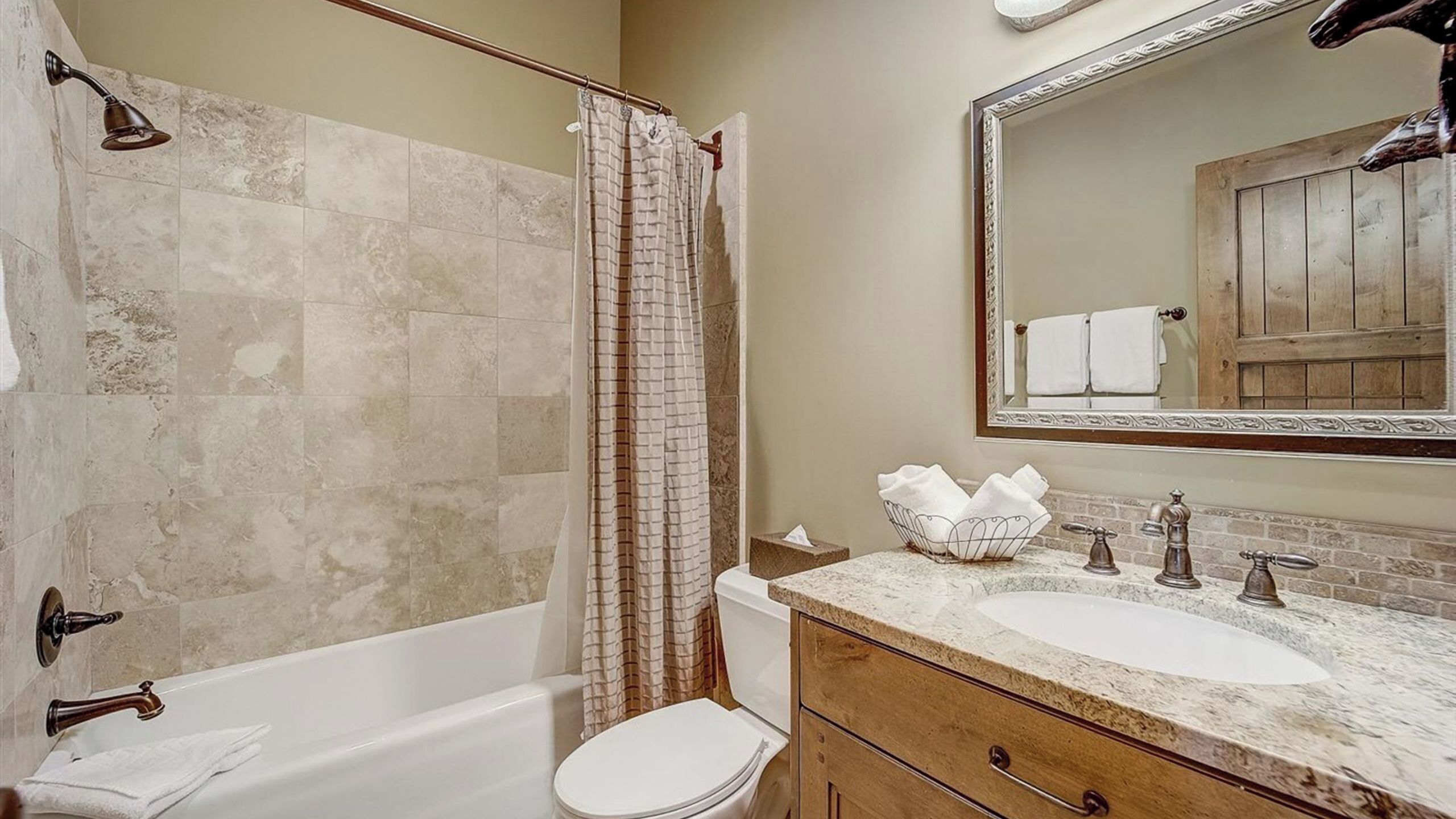 A bathroom with a bathtub, a toilet, a sink with a mirror, and a shower curtain.