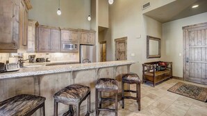 A spacious kitchen with a large island, wooden cabinets, and bar stools. - Mont Cervin #33 by Avantstay Luxury Ski in Ski out Home in Park City! (Park City)