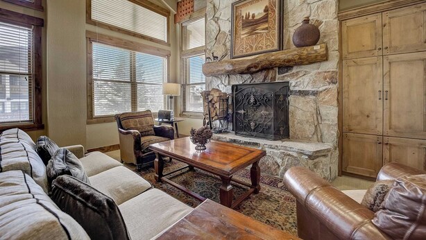 A living room with a stone fireplace, leather sofas, and a wooden coffee table. - Mont Cervin #33 by Avantstay Luxury Ski in Ski out Home in Park City! (Park City)