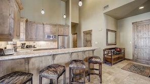 A kitchen with wooden cabinets, a granite countertop, and bar stools. - Mont Cervin #33 by Avantstay Luxury Ski in Ski out Home in Park City! (Park City)