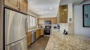 A kitchen with stainless steel appliances, wooden cabinets, a granite countertop, and a tiled backsplash. - Resort Plaza #5065 by Avantstay Ski-in/ski-out Condo in Park City Mountain Resort (Park City)