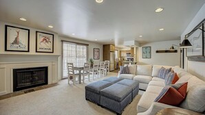 A spacious living room with a fireplace, dining area, kitchen, and a large couch with multiple pillows. - Resort Plaza #5065 by Avantstay Ski-in/ski-out Condo in Park City Mountain Resort (Park City)