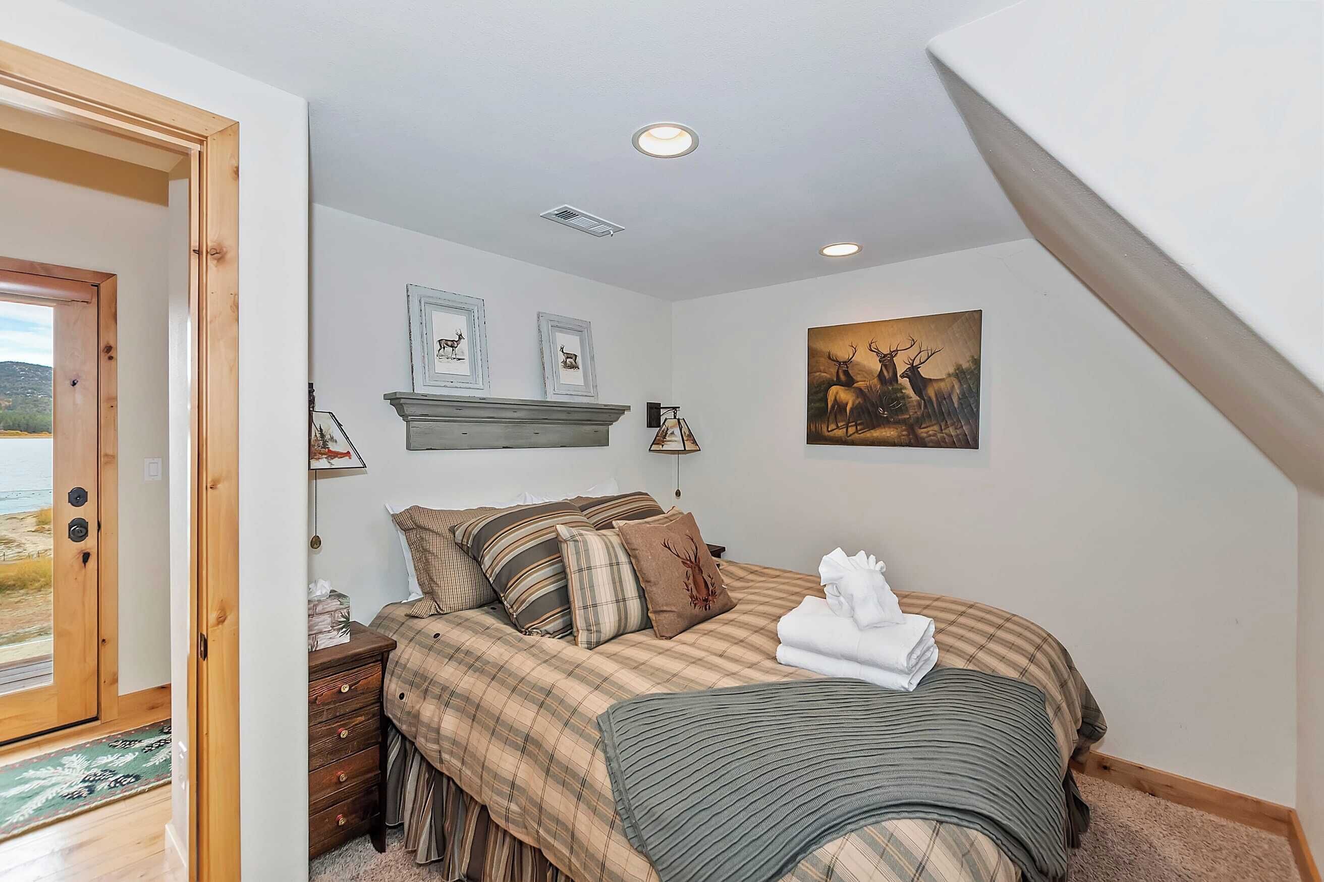 A bedroom with a bed, a nightstand, a dresser, and a painting on the wall.