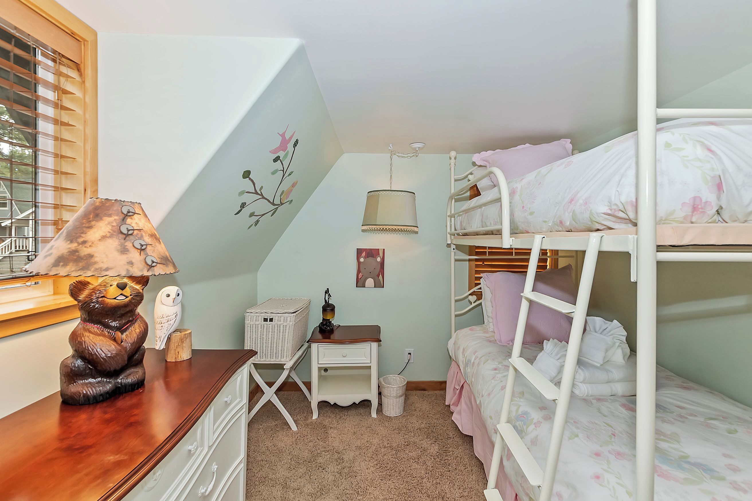 Habitación infantil con literas, un escritorio con lámpara, una silla pequeña y adornos en la pared.