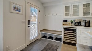 Una cocina moderna con armarios blancos, horno empotrado y cafetera.