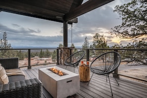 Une terrasse couverte avec un foyer, des sièges d’extérieur et une vue sur le paysage.