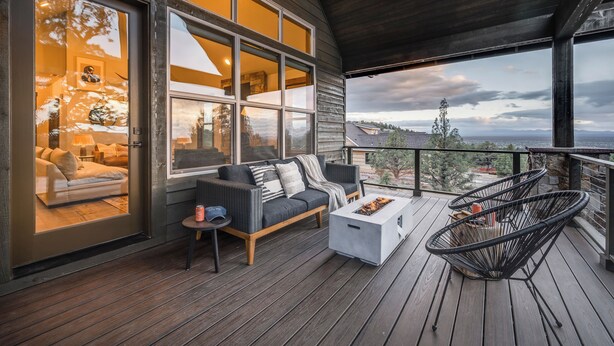 A wooden deck with a sofa, chairs, and a fire pit.