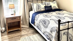 A bedroom with a bed, a nightstand, a lamp, a ceiling fan, and a window with curtains. - LOCATION! | Walk to Stadium and Toomer’s | Cozy 4BR Condo in the Heart of Auburn (Auburn)