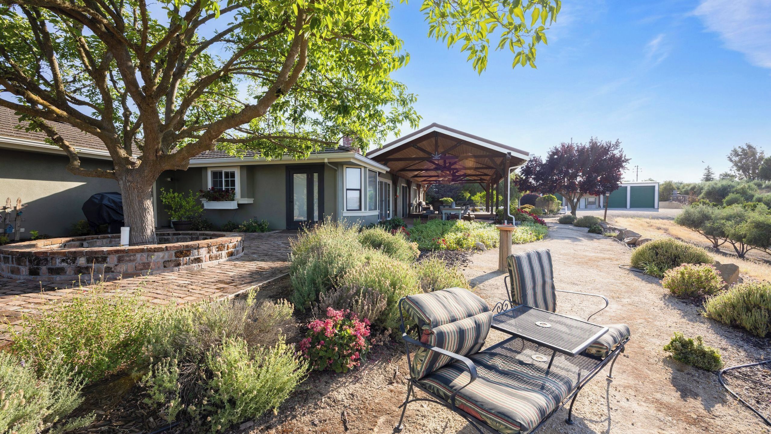 A house with a covered patio, outdoor seating, and a landscaped garden.