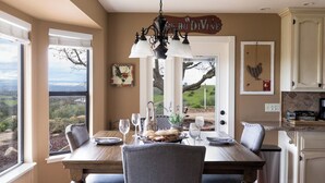 A dining area with a view of the countryside, a chandelier, and a sign reading 'Ancho Divine.' - 4.5 Acre Secluded Ranch w/ Panoramic Views Fire Pit Olive Ranch by Avantstay (Paso Robles)