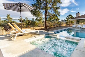 A swimming pool with a hot tub, lounge chairs, and an umbrella. - Mojave Moon by Avantstay Modern & Bright JT Home in Great Location w/ Pool & Hot Tub (Yucca Valley)