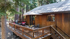 A wooden cabin with a deck, outdoor seating, and a grill. - Whiskey Springs by Avantstay Classic Cabin Near Tahoe Donner Ski Area! (Truckee)
