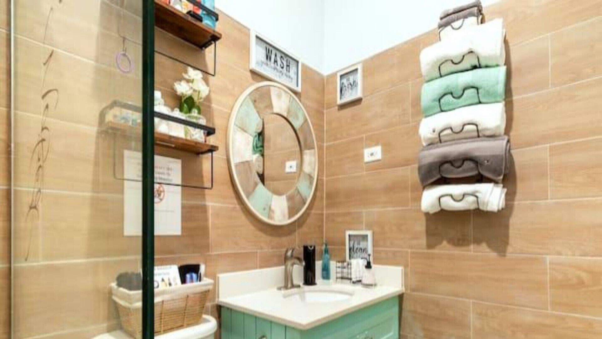 A bathroom with a round mirror, a sink, and a towel rack.