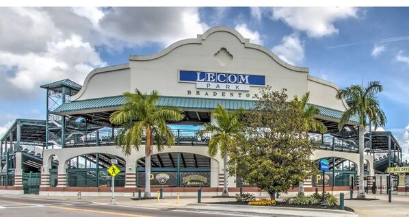 El estadio de béisbol Lecom Park con un letrero llamativo, un pasillo cubierto y un área de estacionamiento.