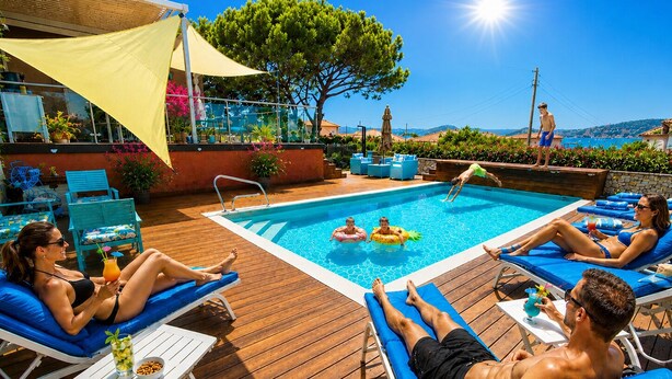 A poolside area with lounge chairs, a pool, and a wooden deck. - GOLDEN VILLA (HYERES)