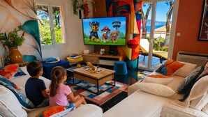 A living room with a television, two sofas, a coffee table, and a large window with a view. - GOLDEN VILLA (HYERES)