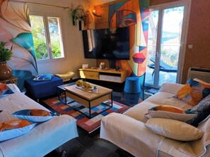 A modern living room with a sofa, coffee table, TV, and artwork.