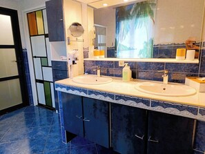 Une salle de bain avec deux lavabos, un grand miroir et un porte-serviettes.