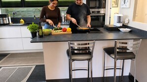 A modern kitchen with two bar stools, a stainless steel oven, and a large island. - GOLDEN VILLA (HYERES)