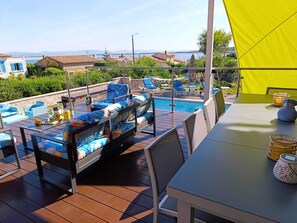 A rooftop terrace with a pool, outdoor furniture, and a view of the sea.