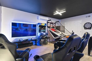 A gaming room with a PS5 console, a basketball hoop, and a dartboard.