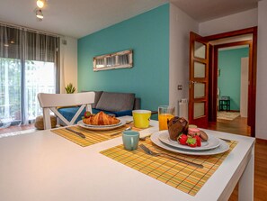 Un coin repas avec une table mise pour le petit-déjeuner, comprenant des croissants, des fraises et un verre de jus d’orange.