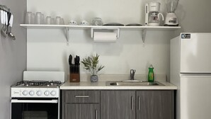 A kitchen with a stove, sink, and refrigerator. There are utensils, a plant, and a coffee maker on the counter. - Ocean View Home with private pool and parking. Sleeps 13 (Rincon)