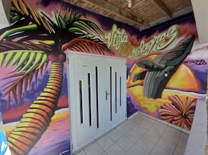 Habitación con un mural vibrante que presenta elementos tropicales y una puerta blanca.