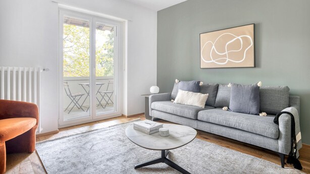 Un salon avec un canapé gris, une table basse ronde et un radiateur.