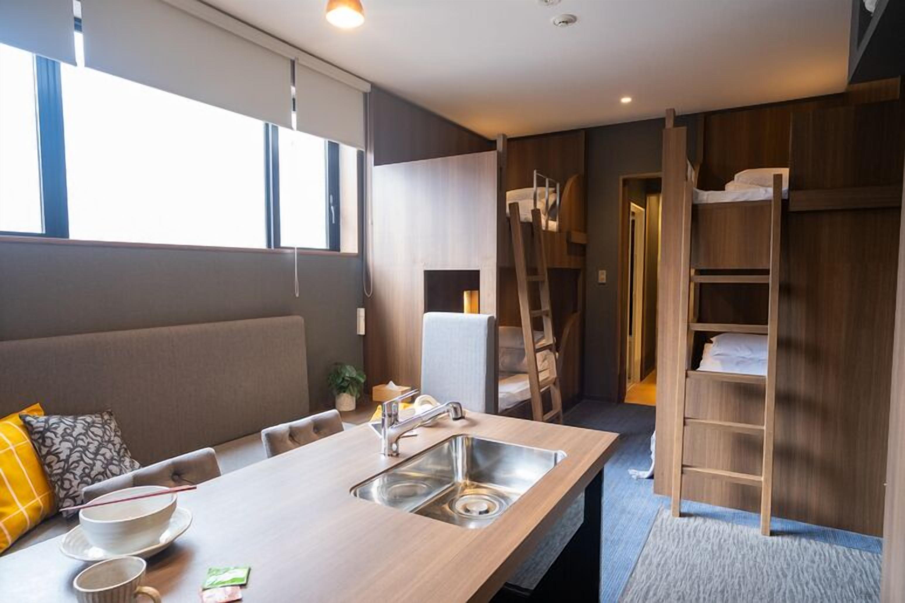 A compact room with a kitchenette, a dining area, and a built-in loft bed.