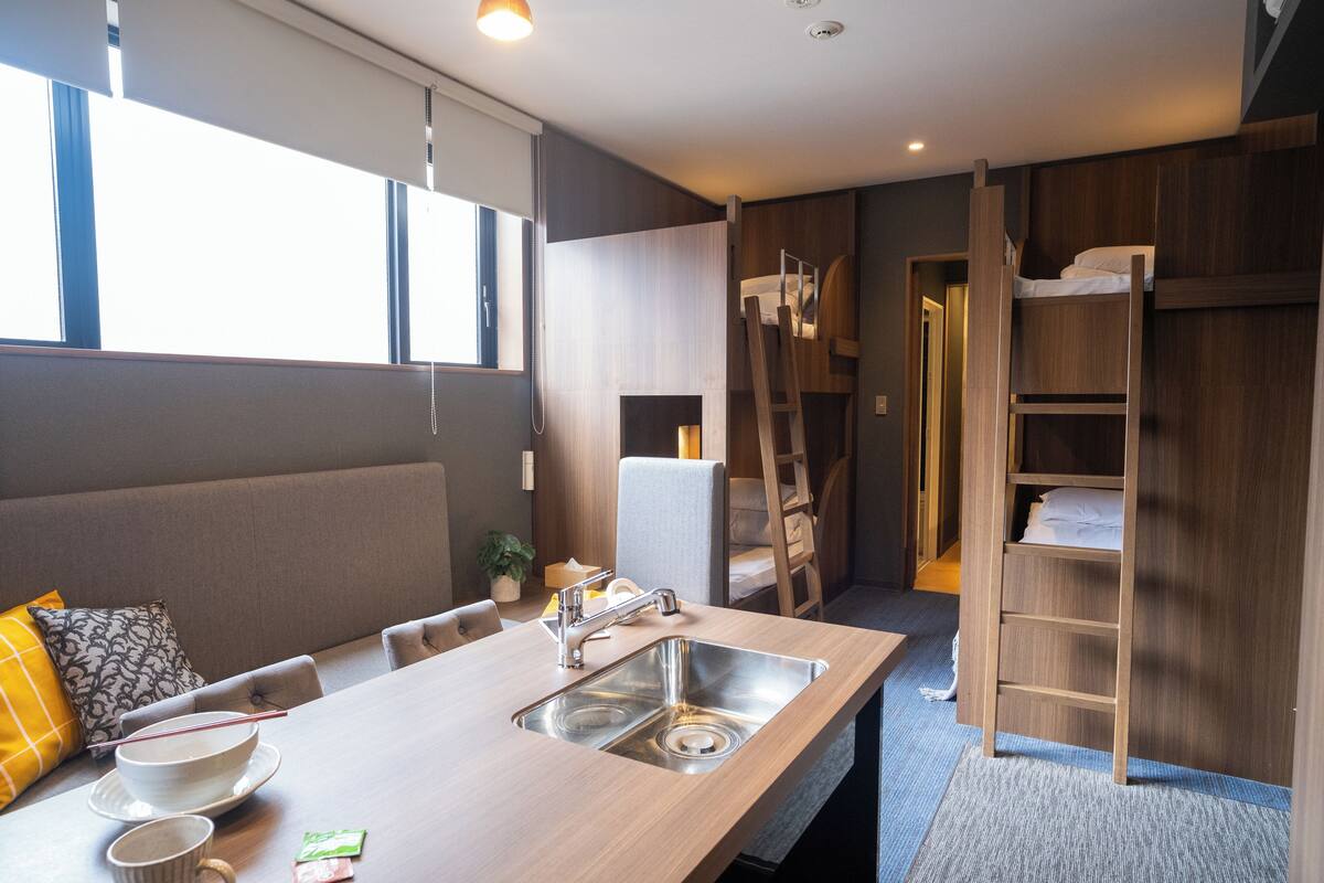 A modern kitchen with a built-in sink, a dining table, and a bunk bed with a ladder.