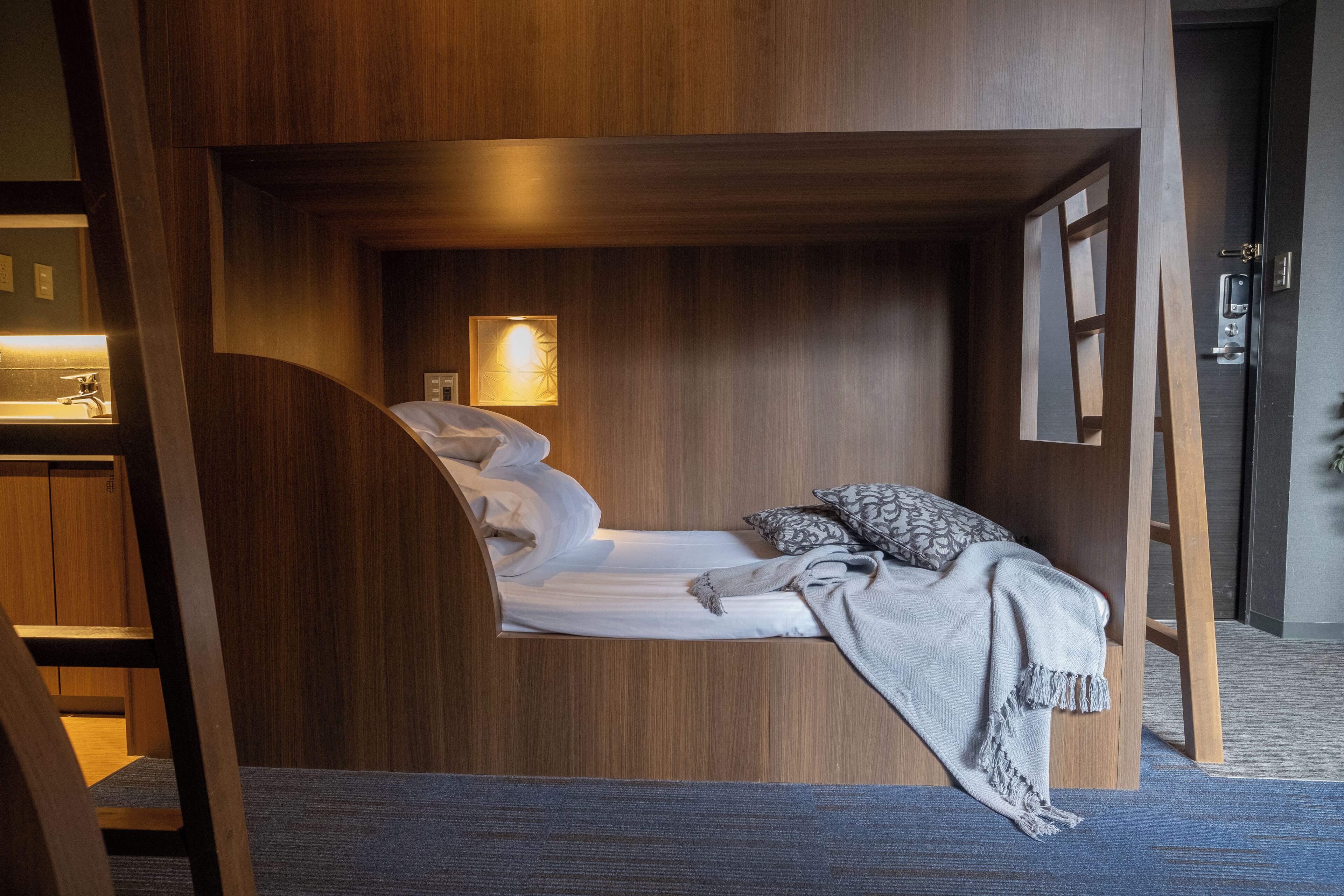 Une chambre à coucher de taille modeste, comprenant un lit, une lampe de chevet et une petite fenêtre.