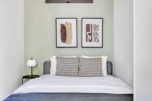 Relax in a serene space with a neatly made bed, side table, and artwork above.