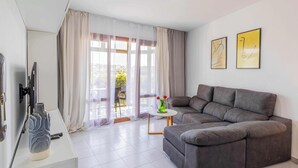 Una sala de estar moderna con un sofá gris, una mesita redonda y un florero con flores.