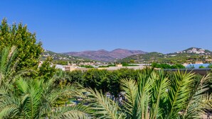 Un pueblo costero con casas, palmeras y montañas al fondo.