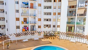 A multi-story hotel with a central swimming pool surrounded by sun loungers and a tiled deck. - Inftour Eurosol Apartamento (Calp)
