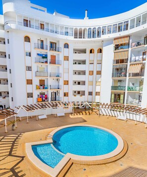 A multi-story hotel with a central swimming pool surrounded by sun loungers and a tiled deck. - Inftour Eurosol Apartamento (Calp)