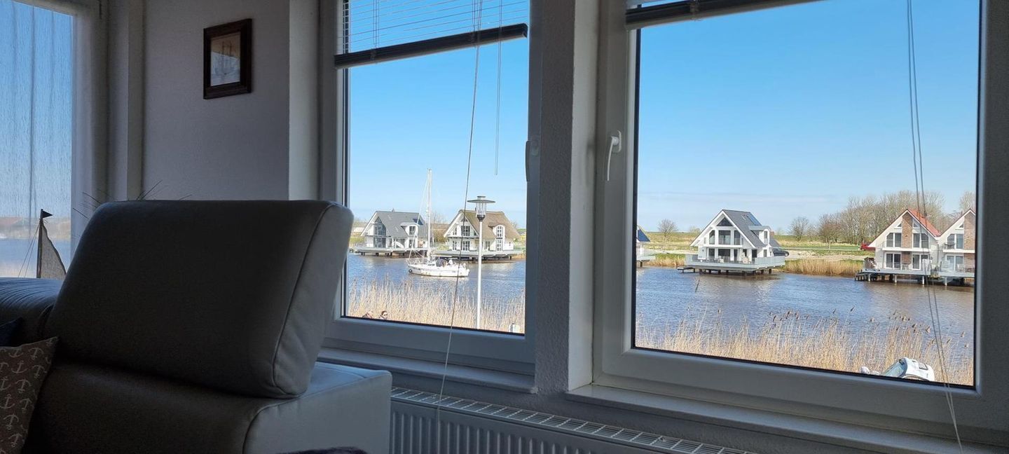 Ett rum med ett stort fönster med utsikt över en kanal där det finns båtar och hus.