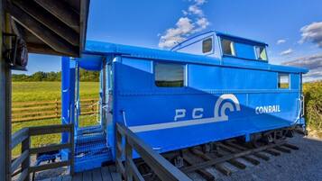 Een blauwe Conrail kluiswagons met een klein hutje en een trap naar de deur.