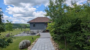 Un sentier de pierres mène à un chalet rustique doté d’un espace extérieur aménagé et offrant une vue sur le paysage environnant.