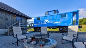 A blue Conrail train car with a picnic table and chairs in front. - The Caboose | Mtn Views | Farm Animals + Sauna (Canajoharie)
