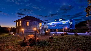 A rustic cabin with a porch and a blue train parked in front. - The Caboose | Mtn Views | Farm Animals + Sauna (Canajoharie)